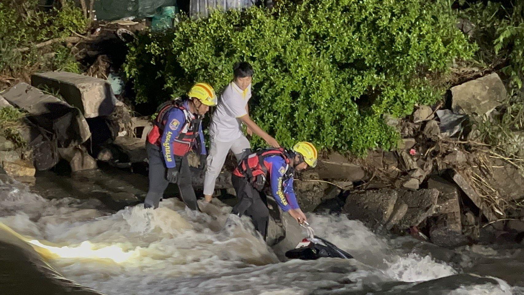 Helfer suchen nach der vermissten Motorradfahrerin im Hochwasser bei Pattaya