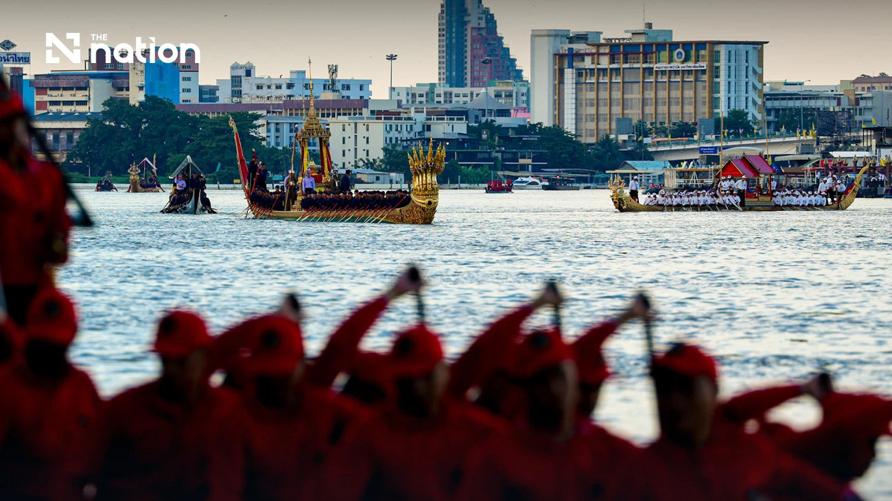 Mehrere königliche Barken auf dem Chao Phraya, im Vordergrund Ruderer in roten Uniformen