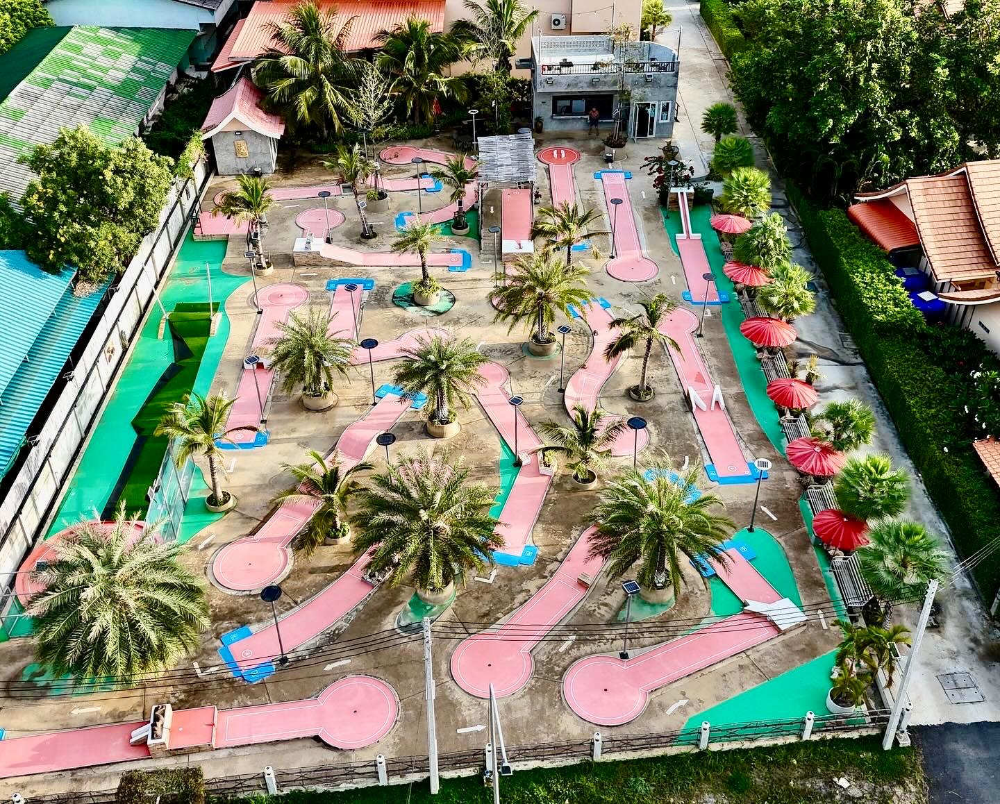 Luftaufnahme der Minigolf-Anlage Minigolf Sport Pranburi mit Palmen und rosafarbenen Bahnen