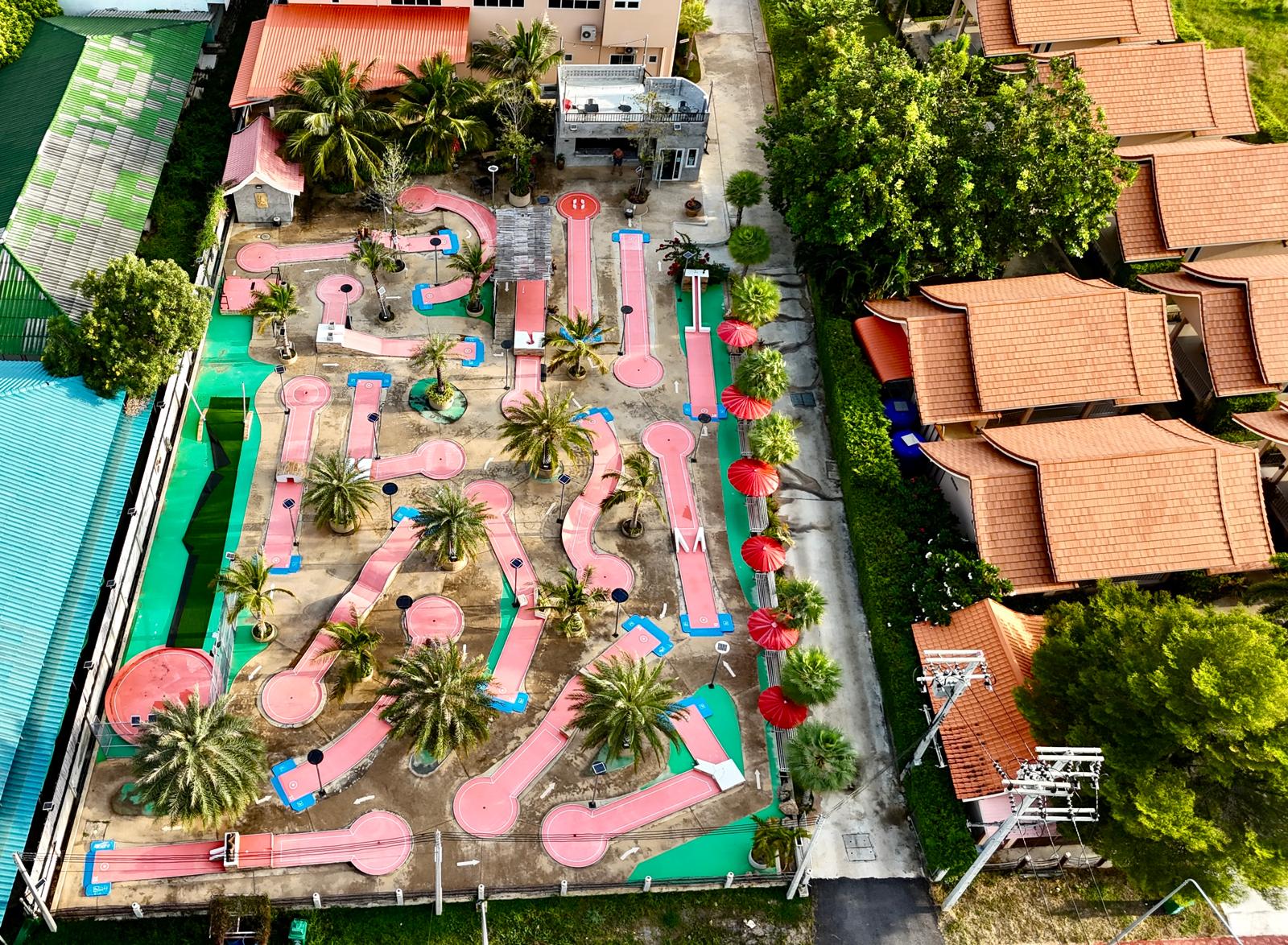 Minigolf-Anlage in Pranburi aus der Vogelperspektive mit Palmen und roten Sonnenschirmen