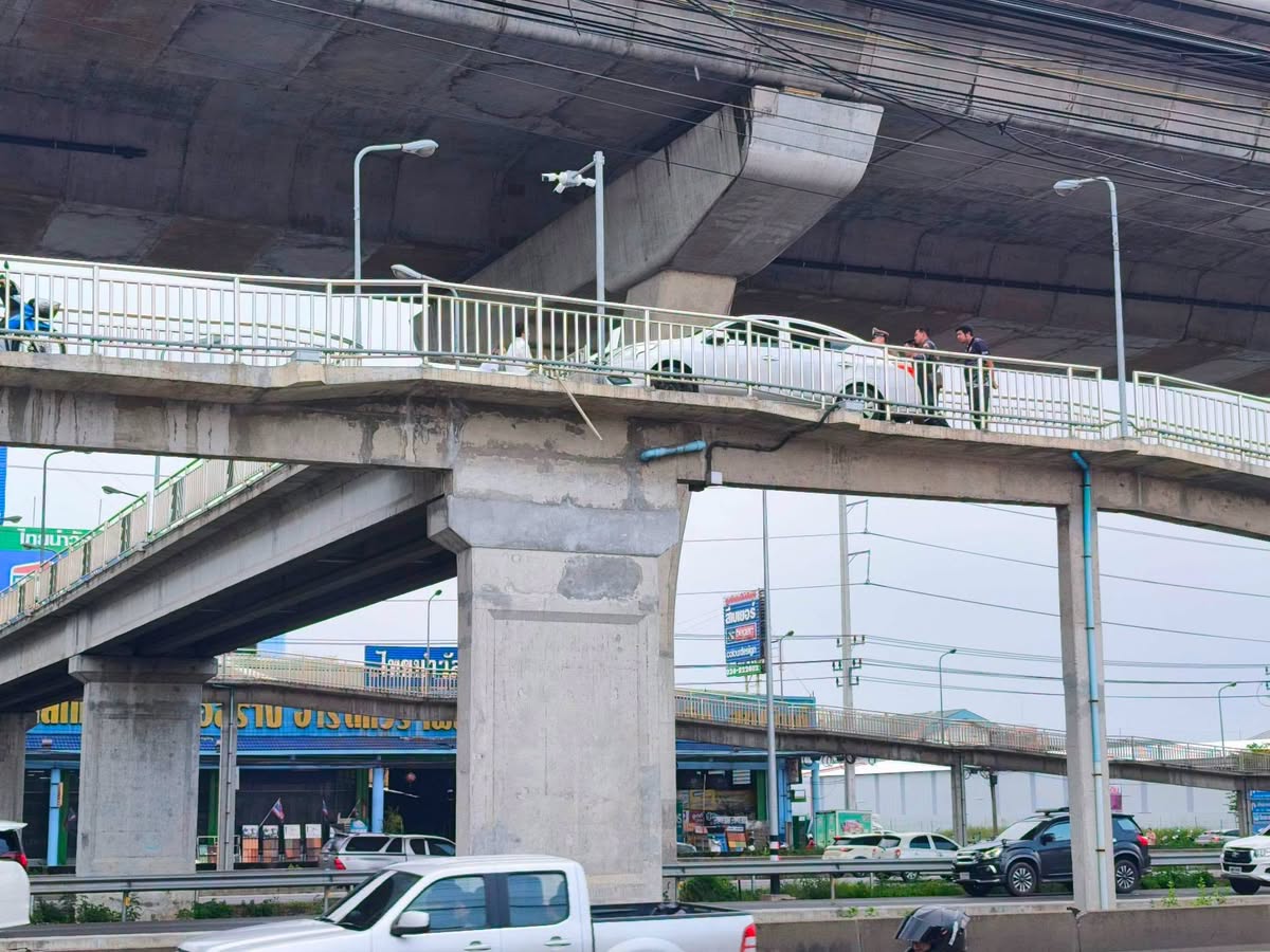 Weißer Sedan steht auf der Motorrad-Rampe über der Rama II in Samut Sakhon, daneben mehrere Personen am Geländer